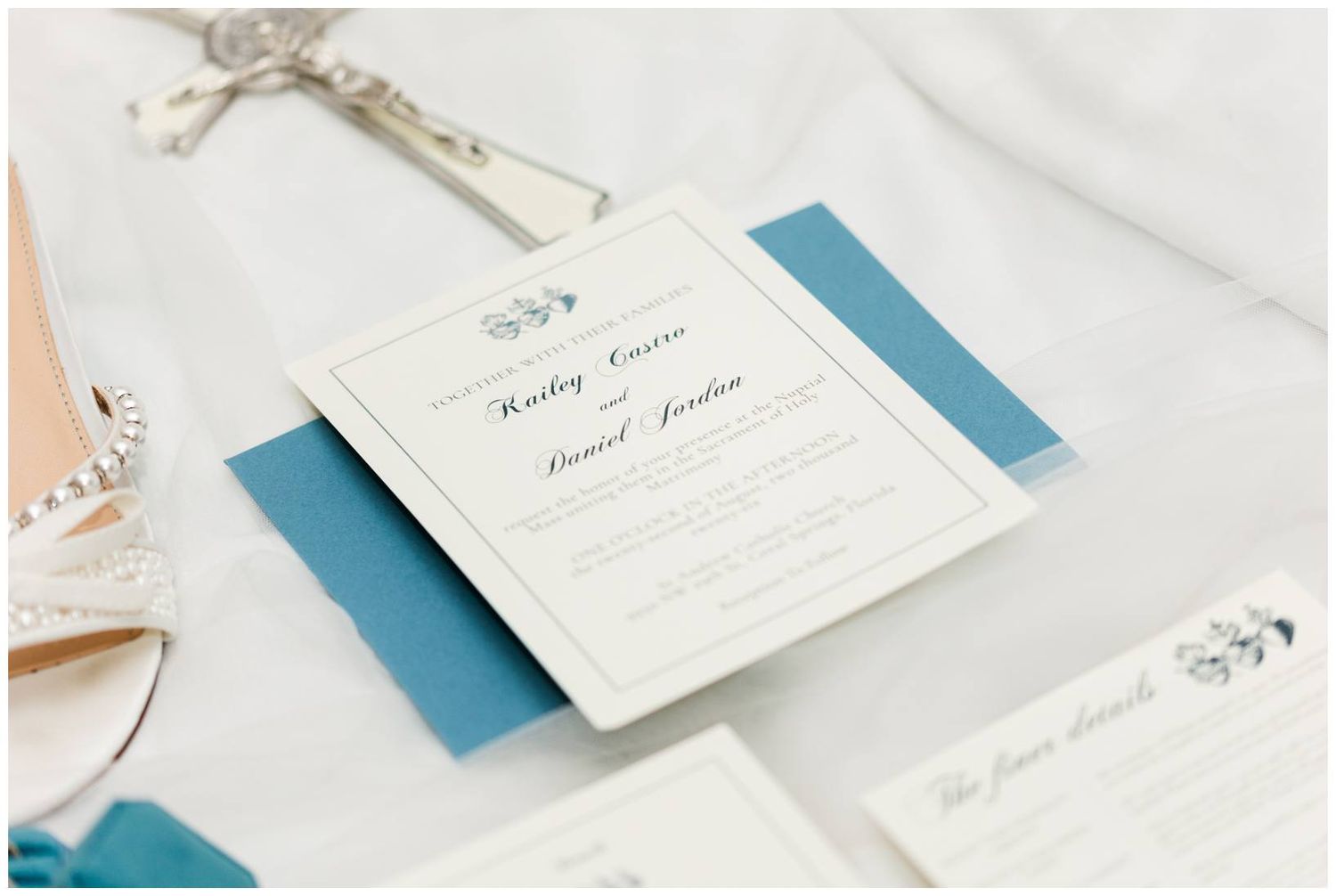 Elegant wedding invitation suite with blue accents and calligraphy script displayed on a white surface.