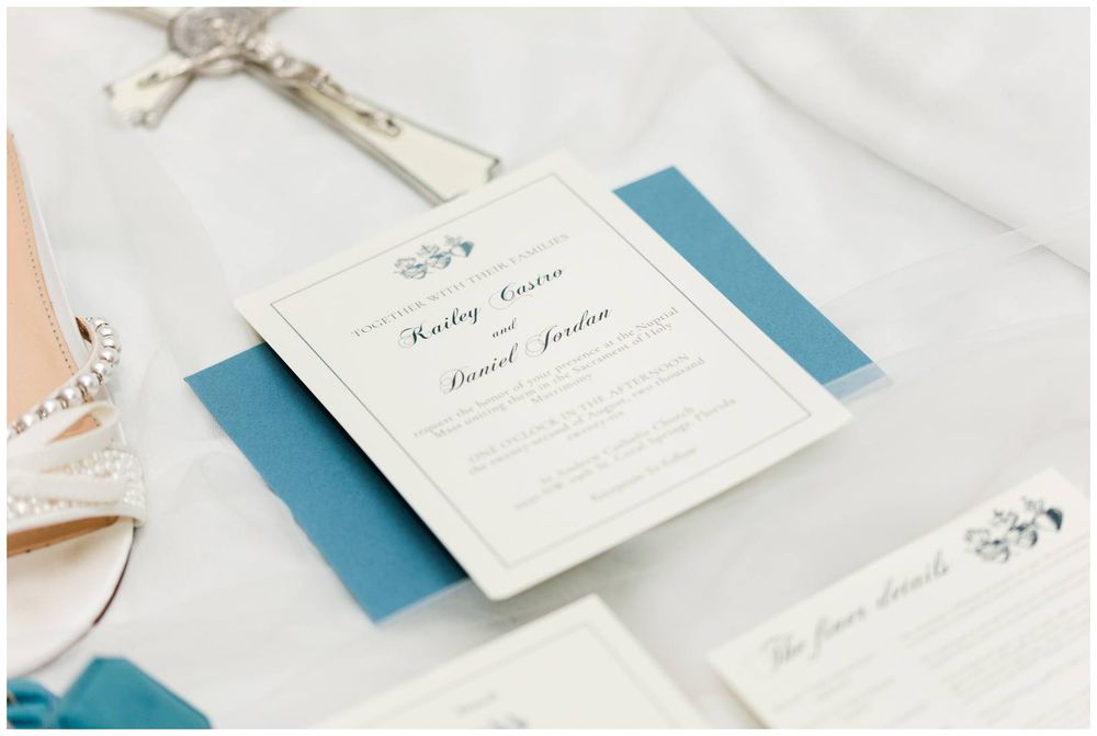 Elegant wedding invitation suite with blue accents and calligraphy script displayed on a white surface.