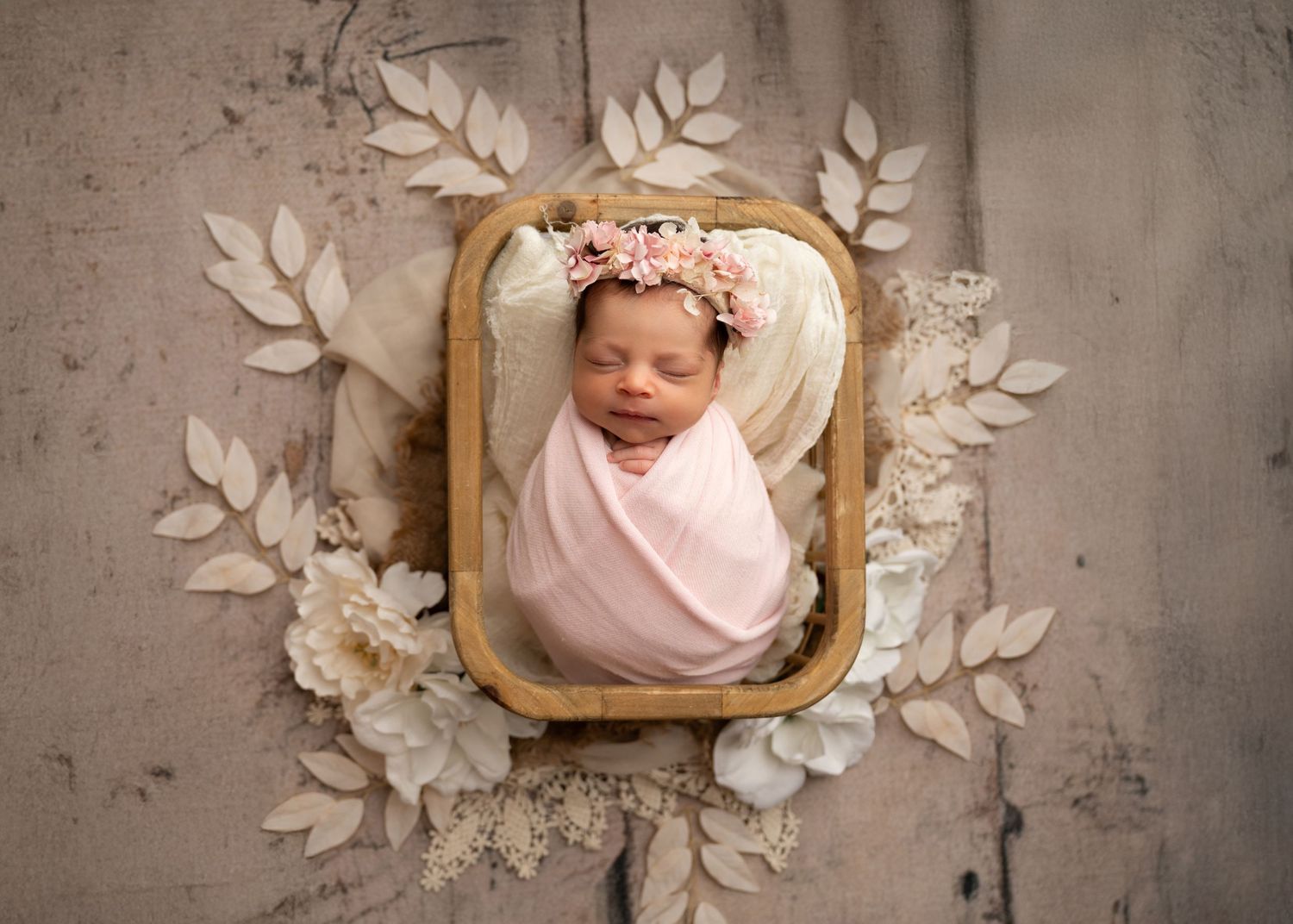 Newborn baby wrapped in pink and posed in a basket during a studio newborn photography session in Linden, New Jersey.