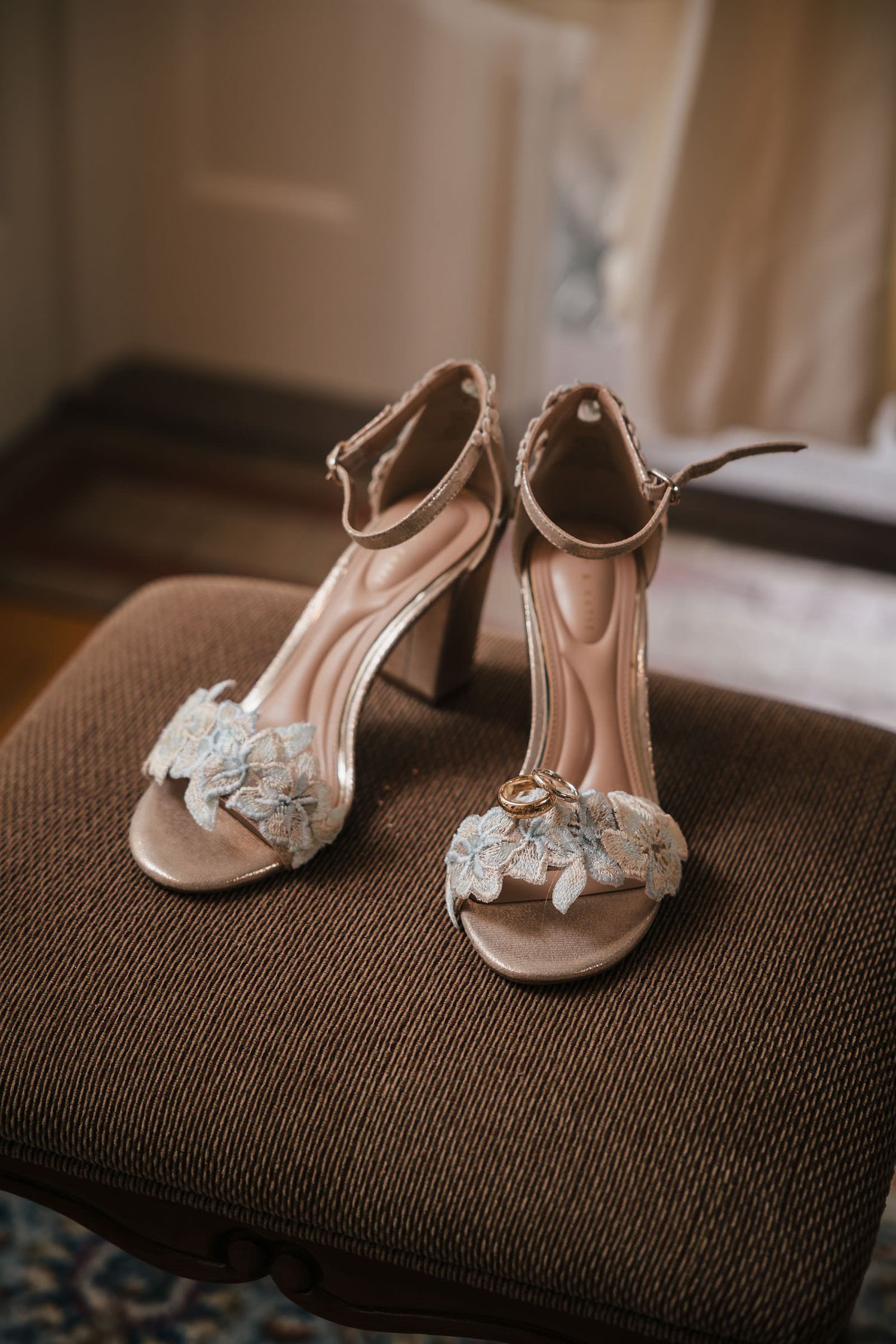 Bride's floral wedding heels with the wedding rings resting on top, photographed at Searles Castle