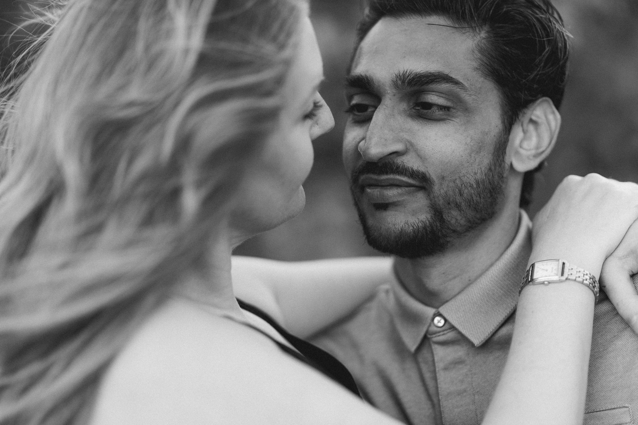 Black and white photo of a couple sharing an intimate moment, woman with blonde hair embracing a man wearing a watch.