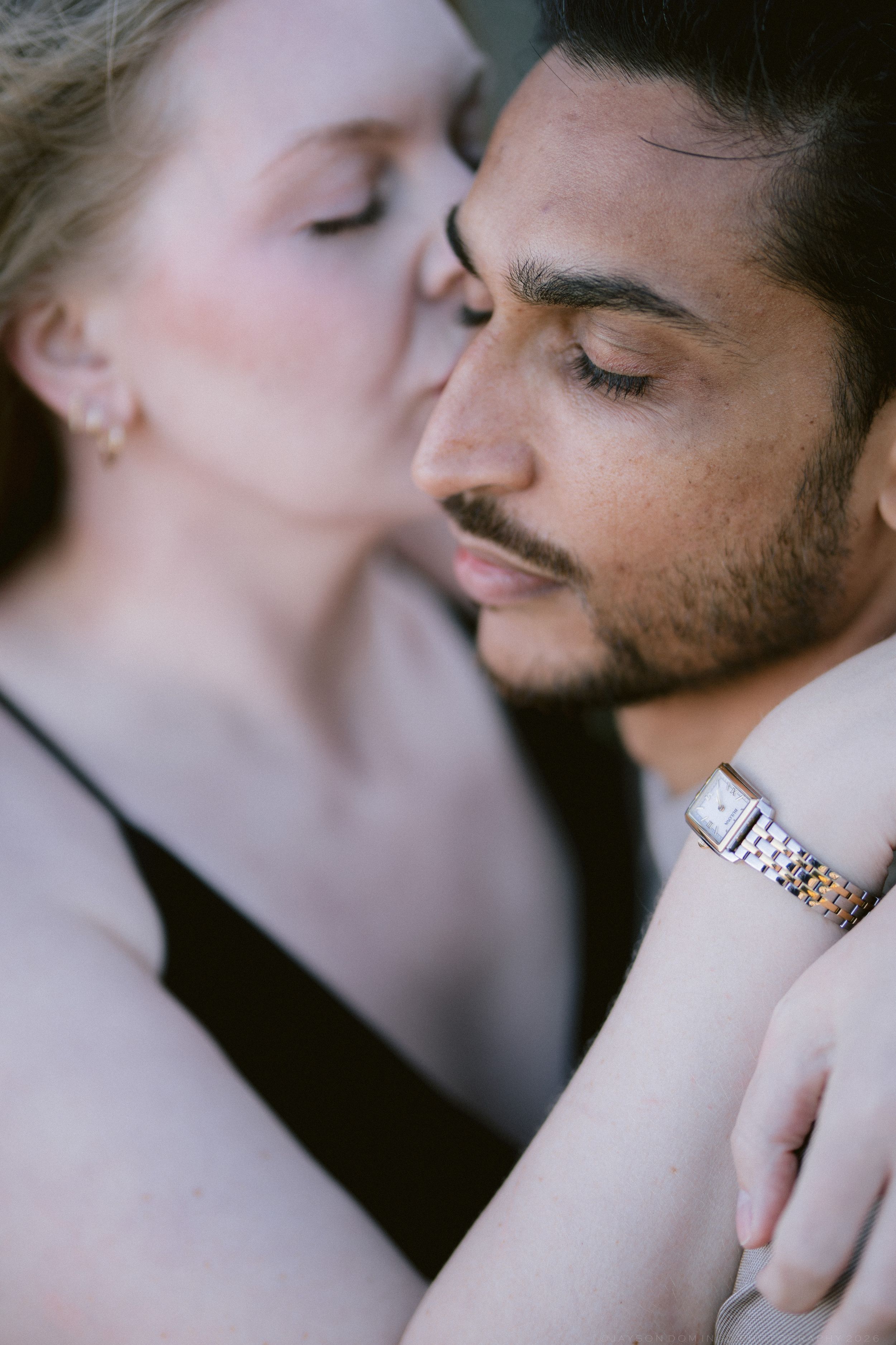 Tender close-up of couple embracing, woman gently kissing mans cheek during romantic photo session.