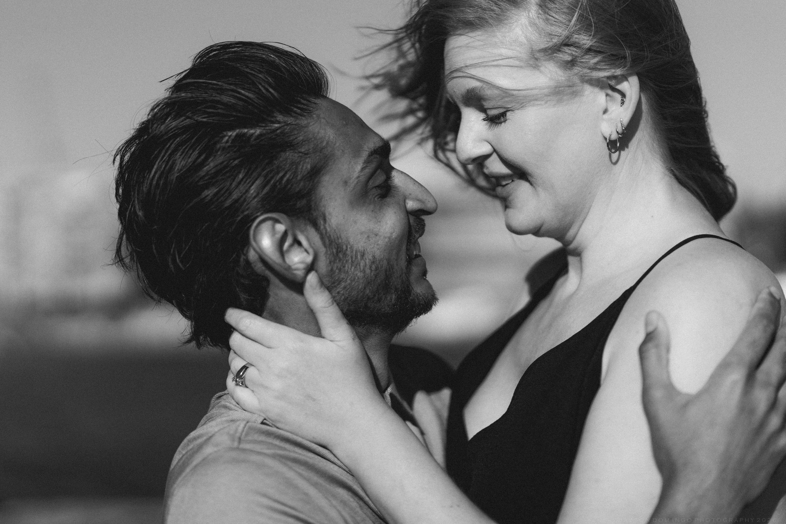 Black and white photo of couple laughing and gazing at each other in a romantic outdoor setting.