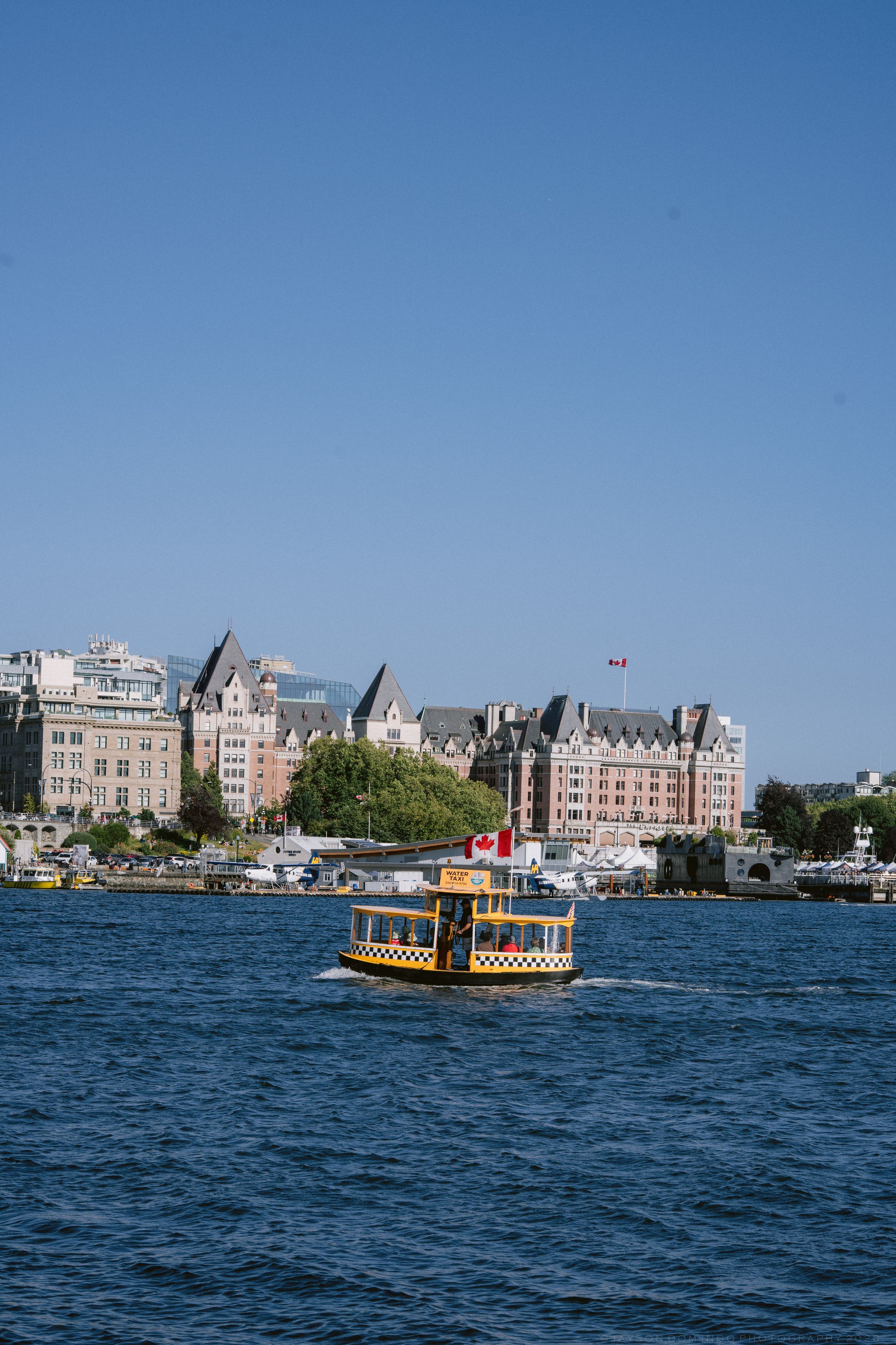 Yellow water taxi crossing Victoria BC harbor with Empress Hotel backdrop.