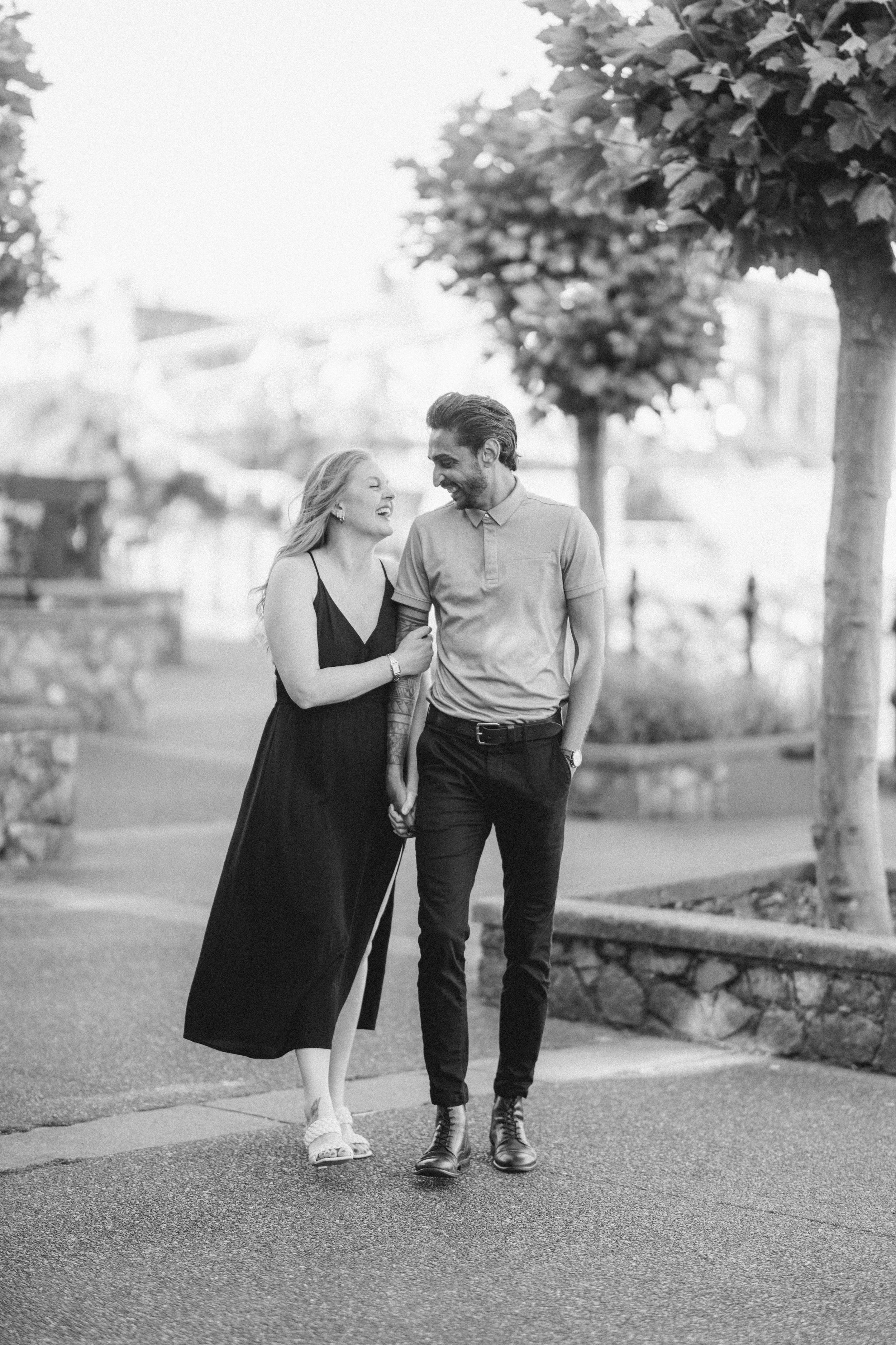 Couple walking and laughing together in black and white park photo.