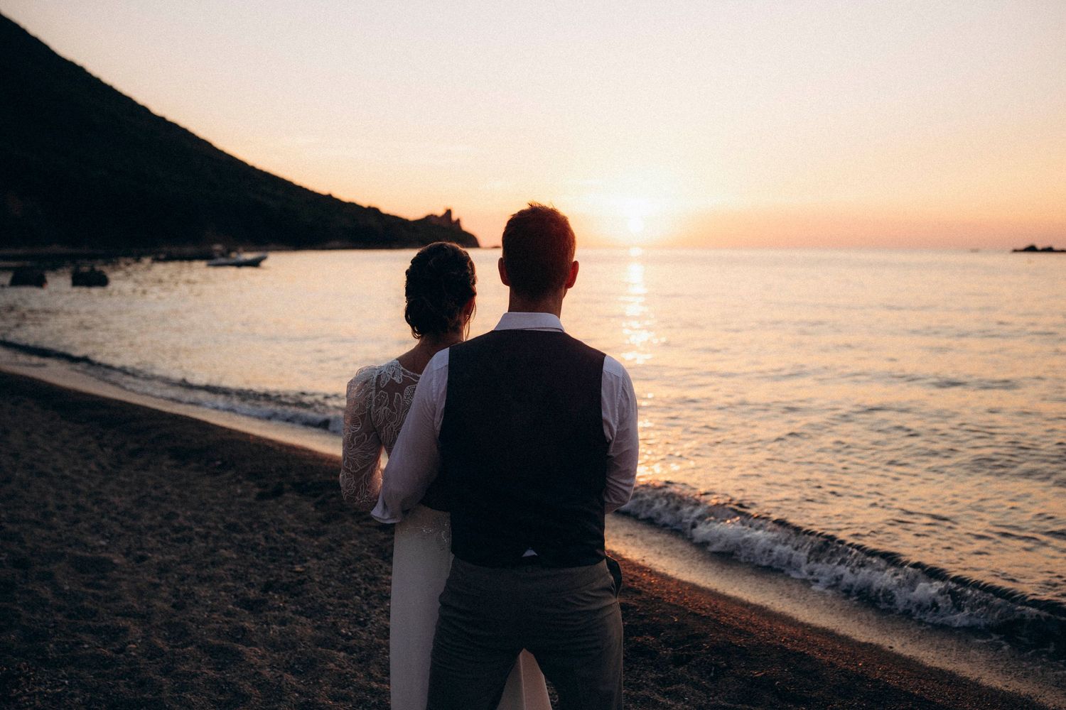 A romantic black and white wedding photograph showing a tender embrace in a natural outdoor setting.