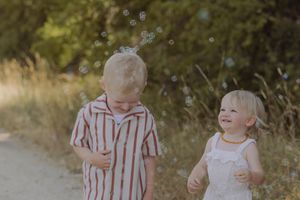 Glückliche Familie mit zwei Kindern bei einem natürlichen Familienshooting auf einem sonnigen Feldweg im Aargau.