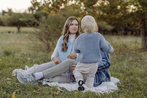 Woman and child sitting on blanket in park having a conversation outdoors in autumn.