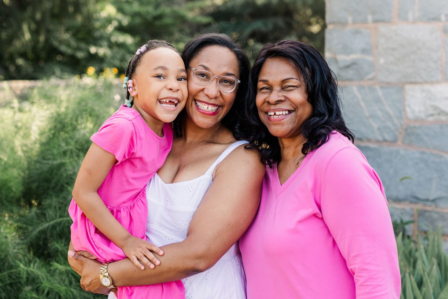 Grandma, mom, and young daughter smile together for a three generations photo.