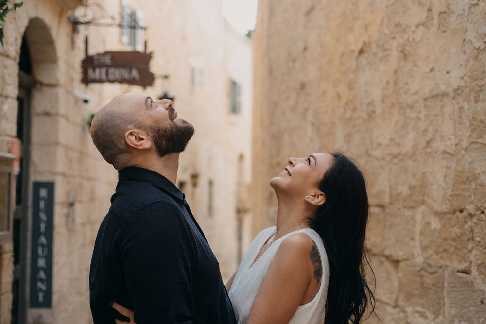 Couple laughing and looking up together in a charming Mediterranean alleyway near The Medina Restaurant.