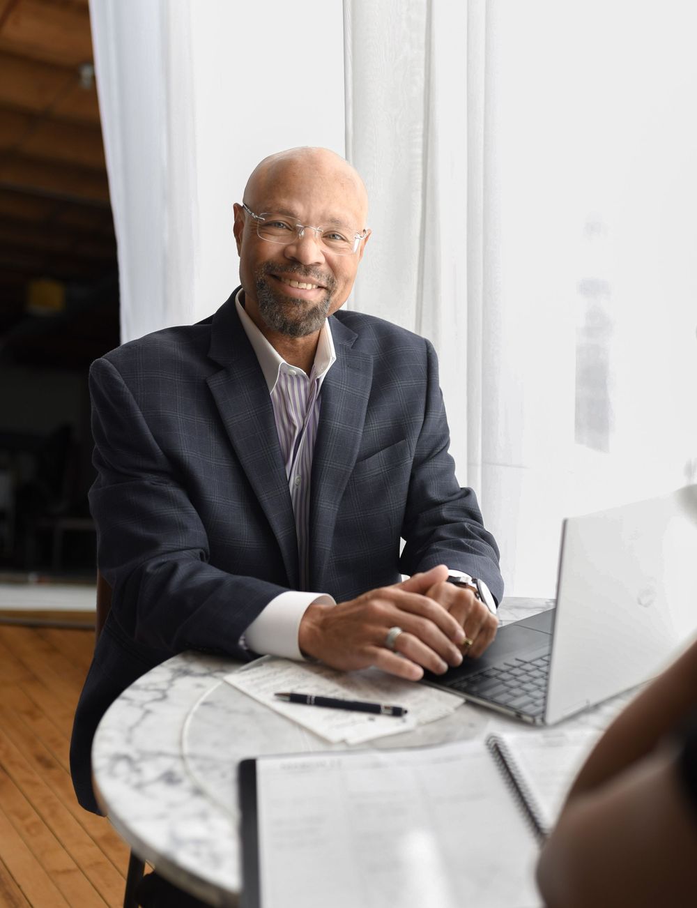 A certified public accountant sitting at a table with laptop during a branding session in a natural light studio.
