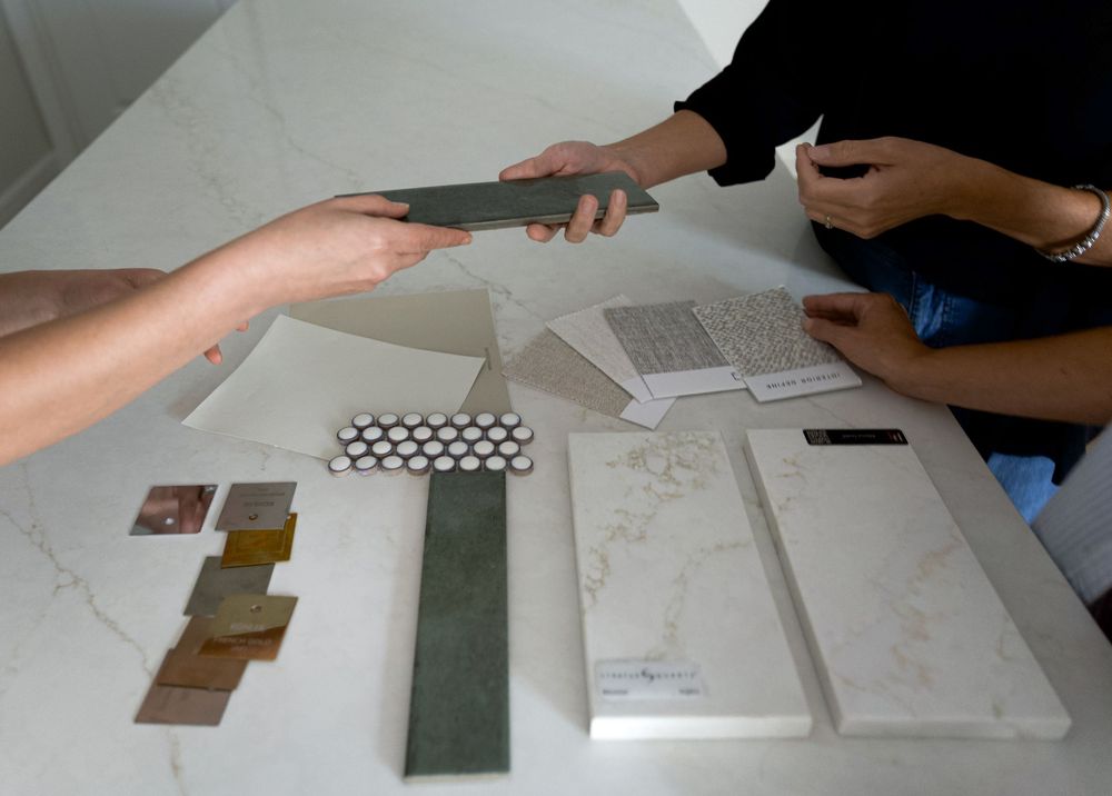 Two people review tile and material samples on a marble table during an interior design branding session.