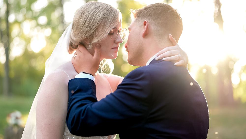 A couple shares a romantic moment in golden sunlight during their outdoor wedding ceremony.