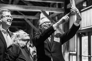 Three people smiling and taking a selfie at an indoor event in a black and white photo.