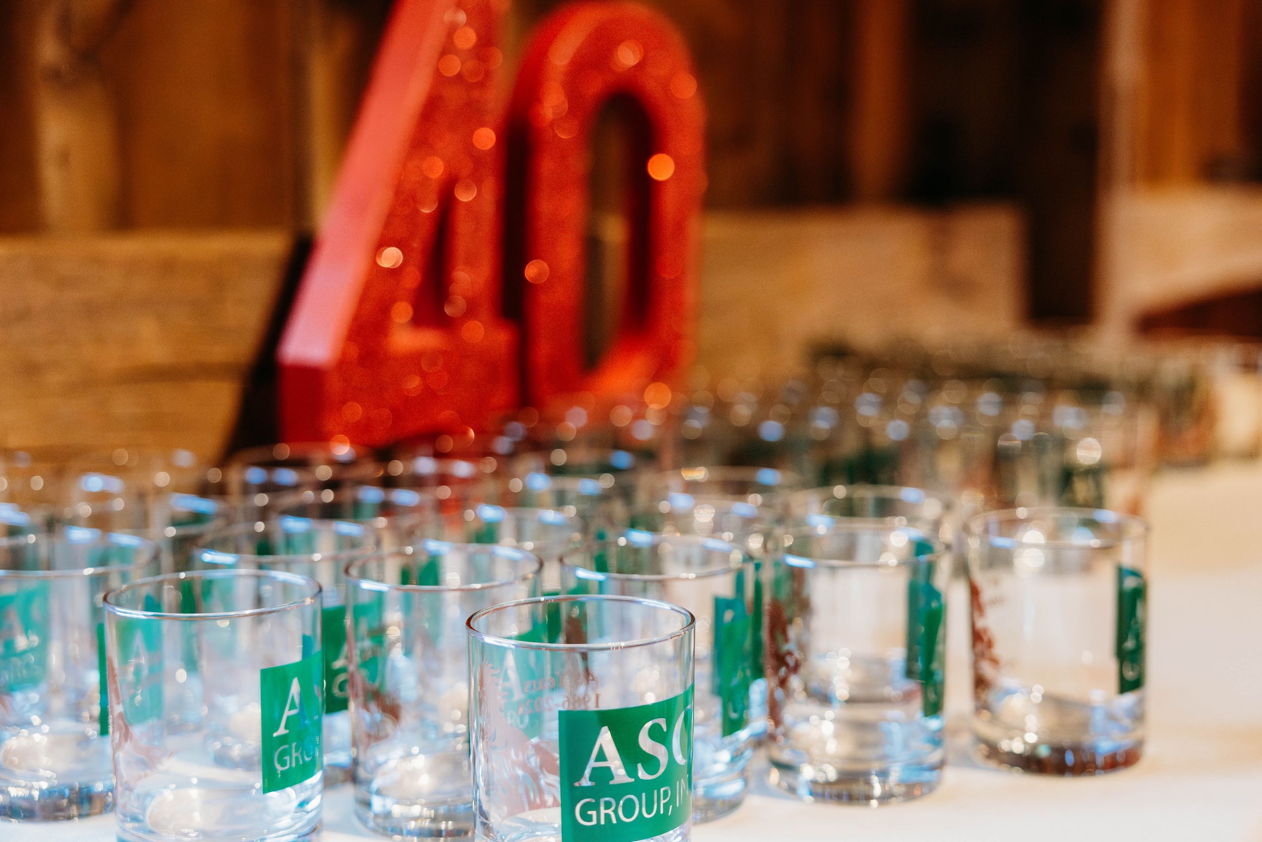 ASG Group 40th anniversary celebration with branded glasses and red balloon numbers on a decorated table.