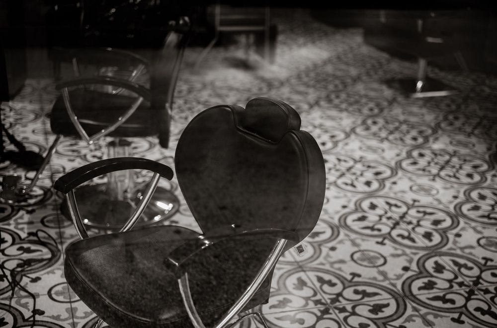 Vintage barber chairs on ornate tiled floor in black and white photography.