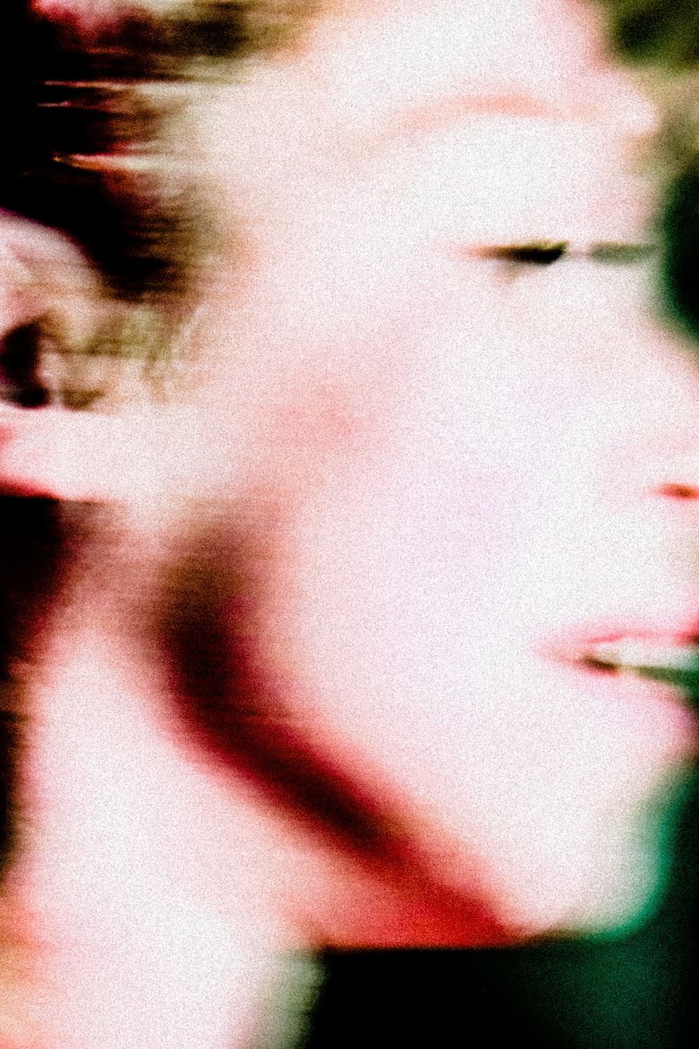 Abstract blurred close-up portrait with glitch effect, showing a face with pink and red tones.