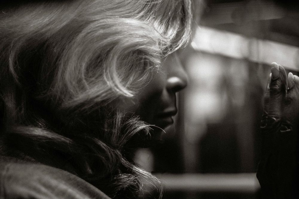 Black and white profile portrait of a blonde woman with flowing hair, looking thoughtfully to the side.