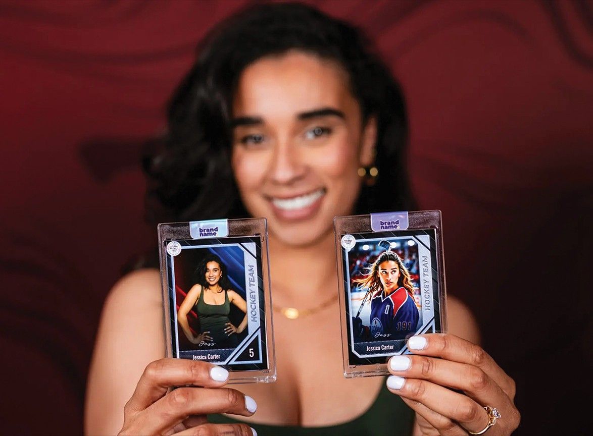 Smiling woman holds up two trading cards in protective cases against a dark red background.
