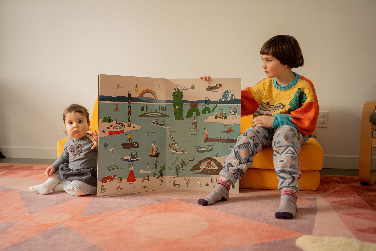A mother holds two young children in a cozy living room, smiling as one child kisses her cheek.