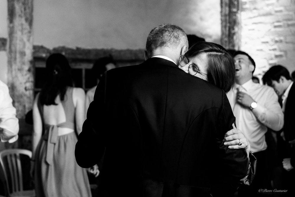 Couple sharing an intimate dance embrace at a wedding reception in a rustic venue, black and white photo.