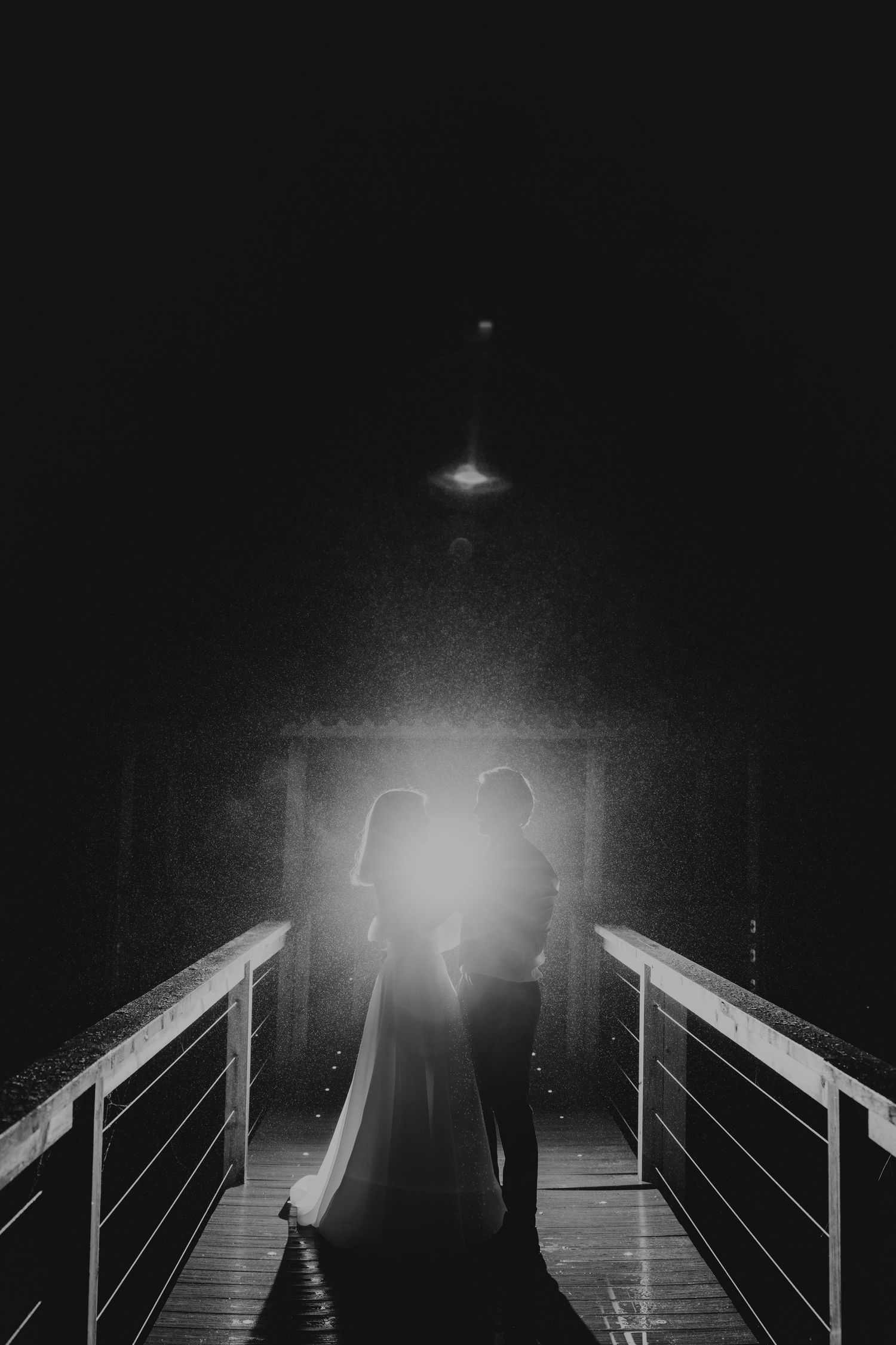 Couple silhouetted on the bridge on the lake at Quantock Lakes.