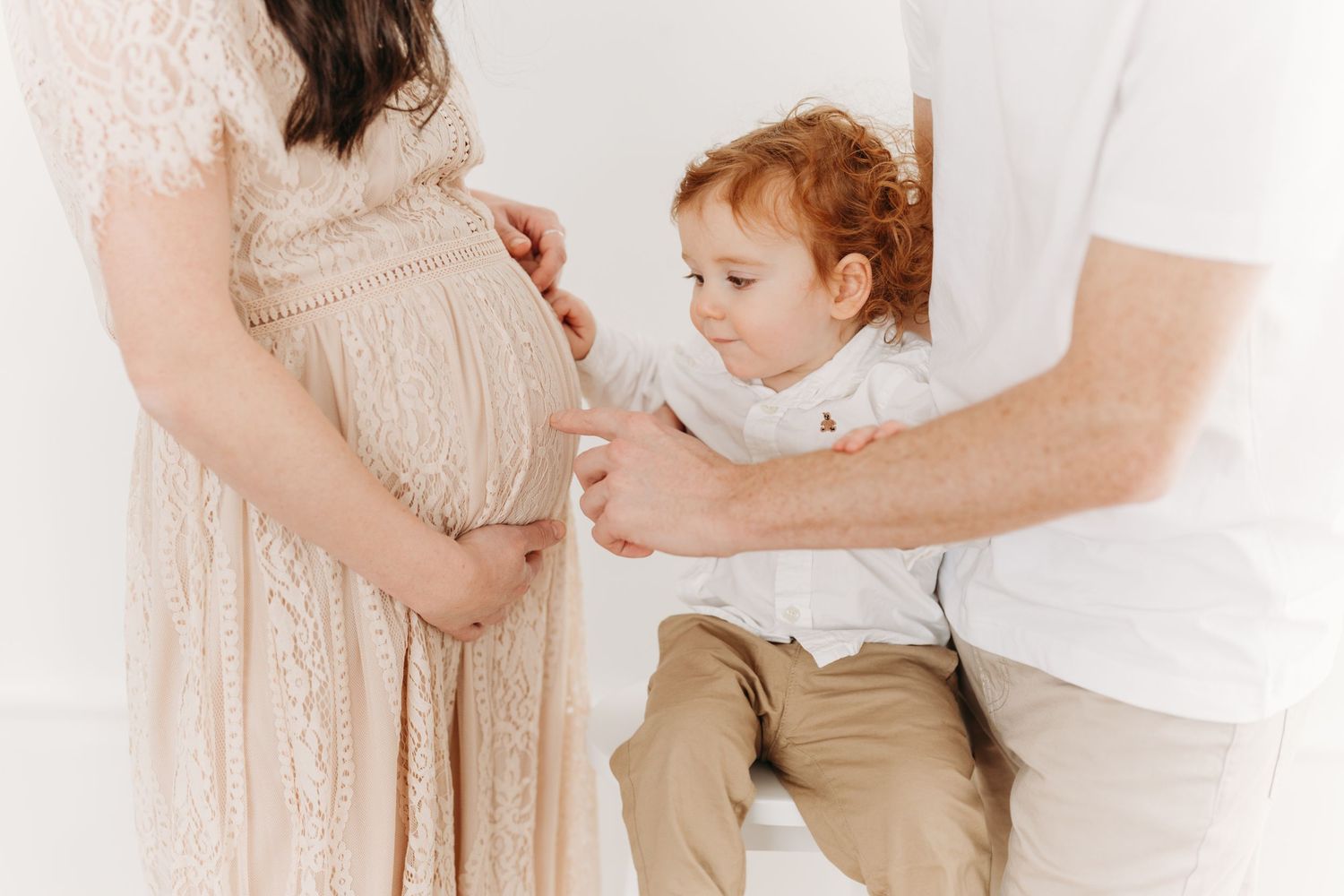futur grand frère qui touche du doigt le ventre de sa maman enceinte