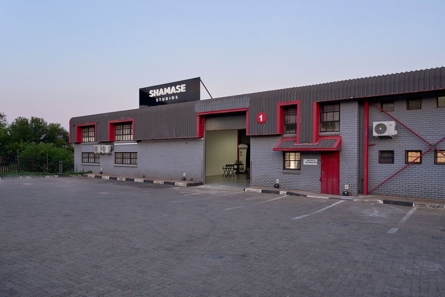 Exterior view of Shamase Studios industrial building with parking lot at dusk in South Africa.