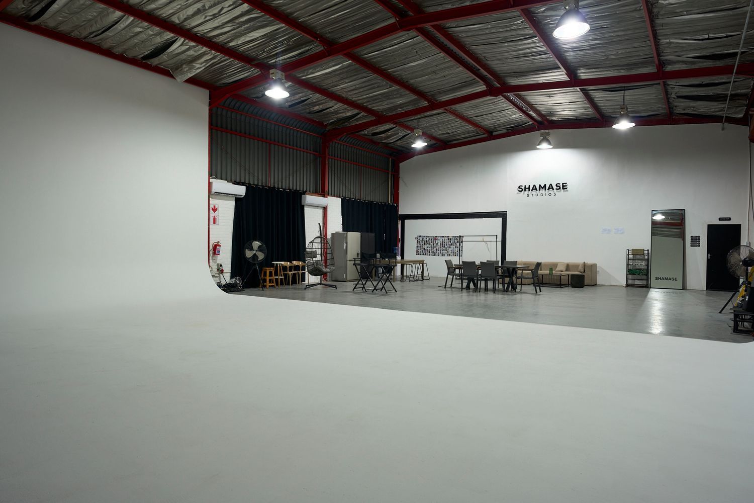 Large professional photography studio with white cyclorama wall, high ceilings, and spacious open floor plan at Shamase Studios.