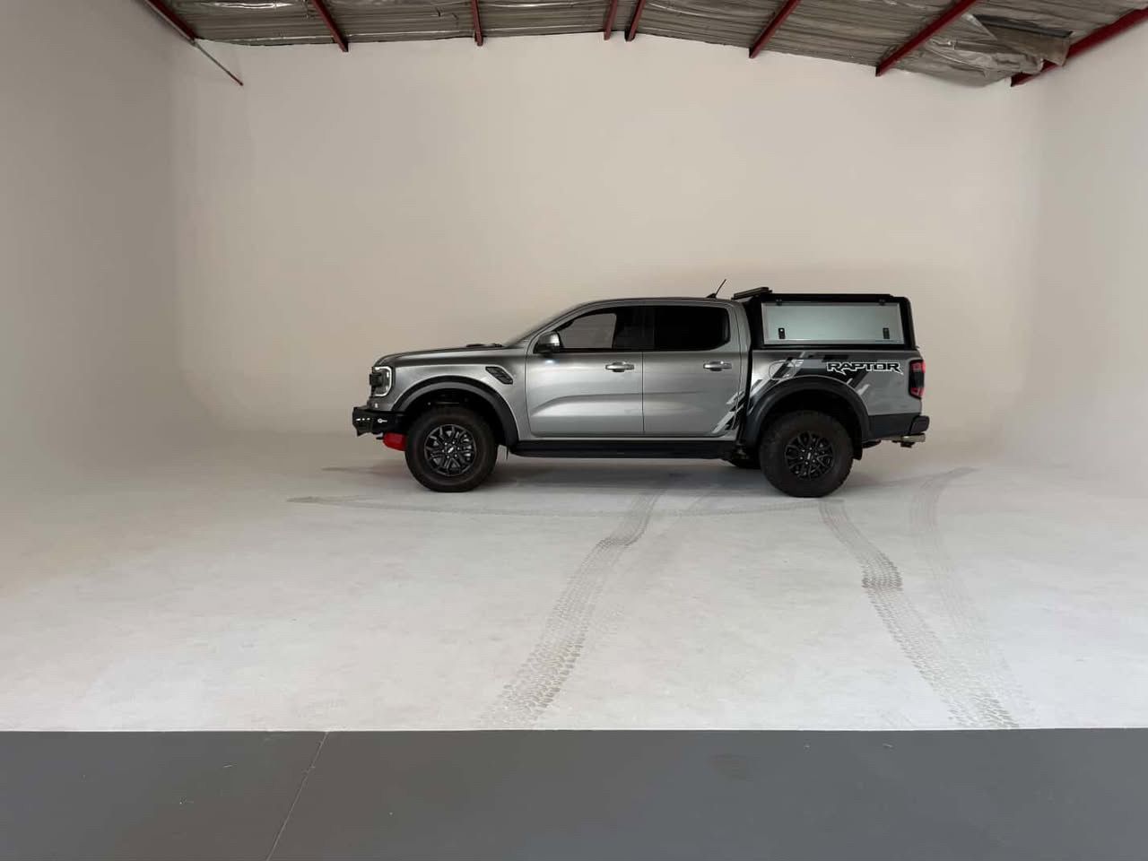 Gray Ford Ranger Raptor pickup truck photographed against white cyclorama backdrop in professional studio.