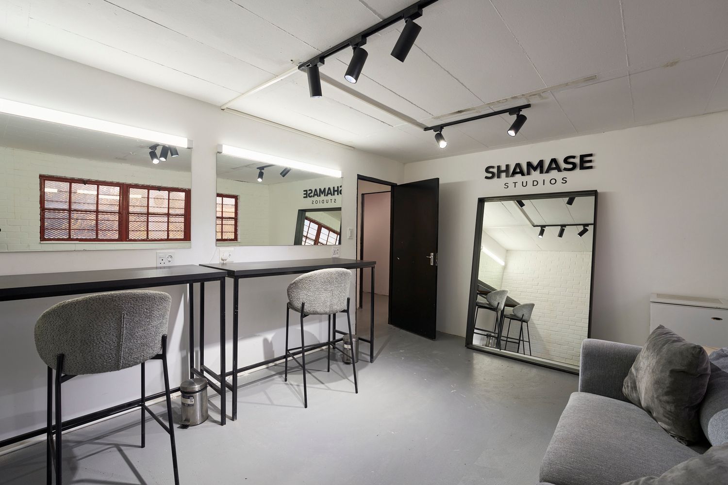 Contemporary studio green room with bar seating, large mirrors, and Shamase Studios branded signage.