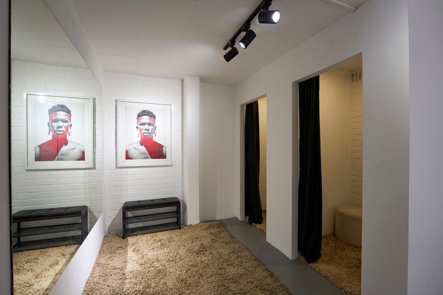 Elegant dressing room corridor with portrait photography, full-length mirrors, and black curtained changing rooms.