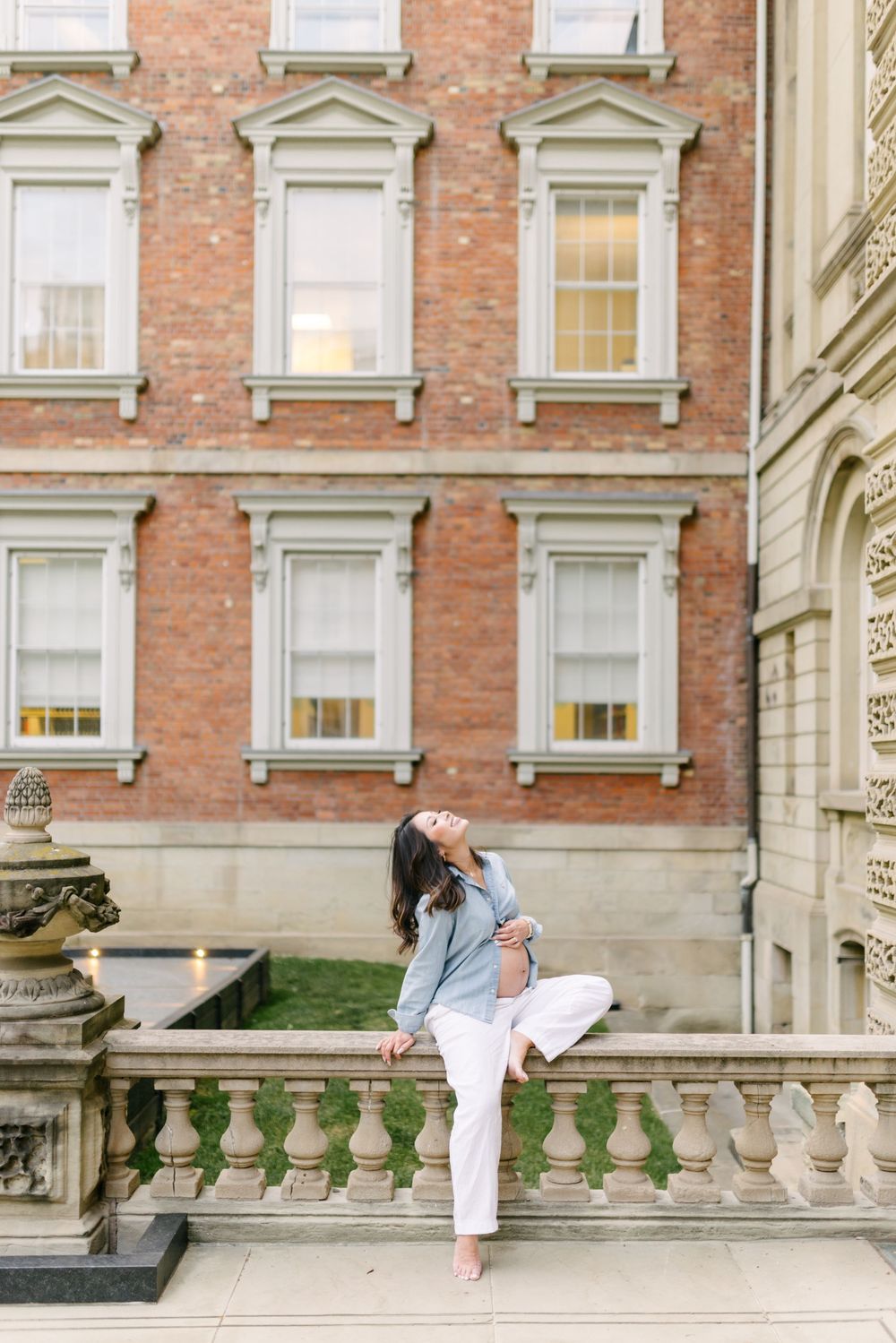 Expectant couple beside a red-brick heritage building in Toronto.
