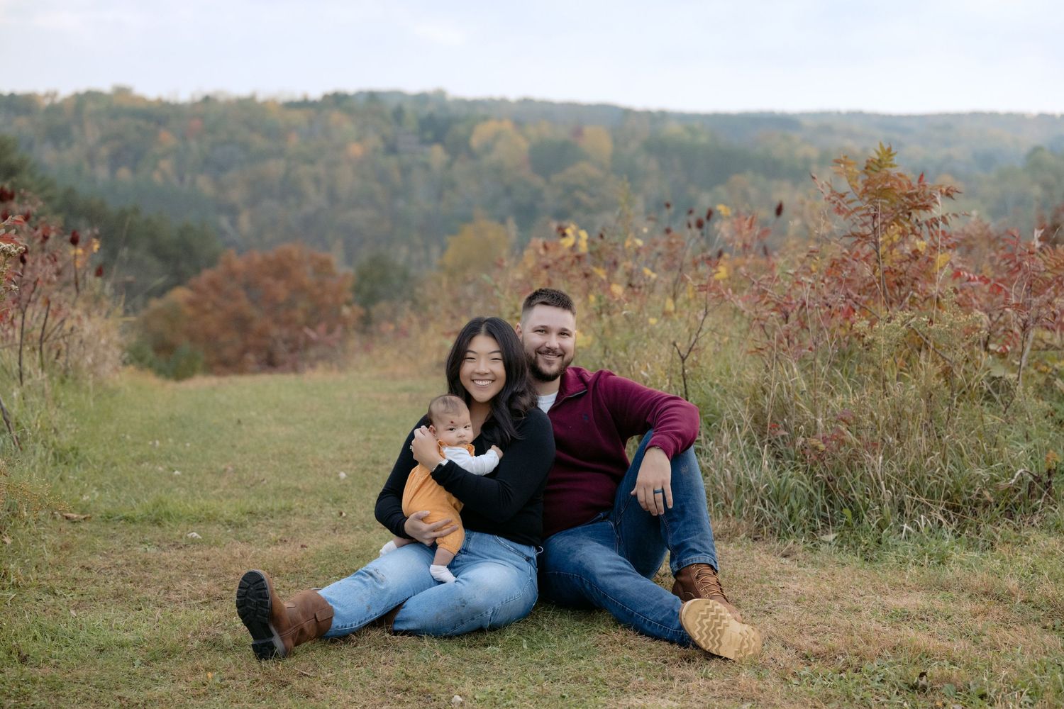 young parents smile at the camera during their first family session with their infant for fall mini sessions in hudson wisconsin