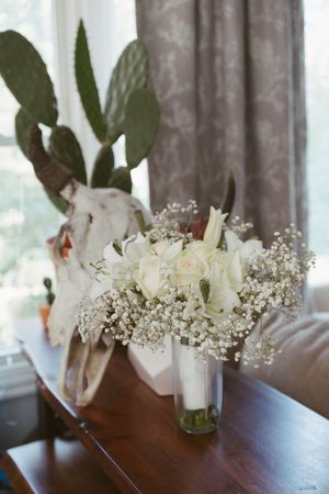 Elegant white rose and baby's breath arrangement with rustic skull and cactus decor.