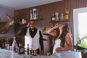 Bride and groom taking celebratory shots together at decorated bar with deer mount.