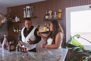 Bride and groom enjoying drinks together at marble bar with eclectic wall decor.