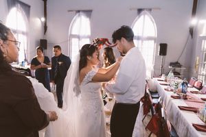 Bride and groom share a tender moment during their wedding reception in an elegant white chapel venue.