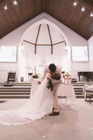 Bride and groom share a romantic kiss at the altar of a white church during their wedding ceremony.