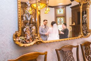 Couple shares wedding vows reflected in an ornate gold-framed mirror in a vintage decorated room.
