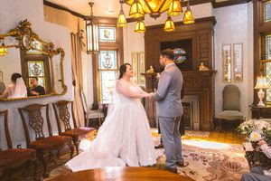 Bride and groom share their first dance in an elegant vintage mansion interior with stained glass windows.