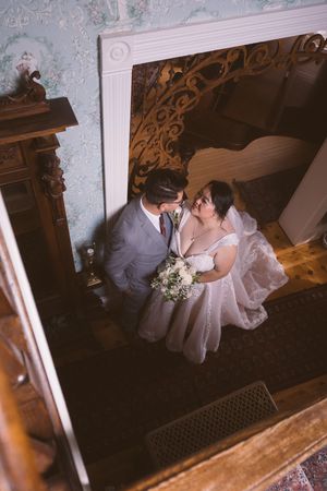 Aerial view of bride and groom sharing a romantic moment in an elegant vintage venue, bride holding white bouquet.
