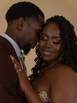 A couple in formal attire shares an intimate forehead-to-forehead moment, the woman wearing a diamond ring and strapless gown.
