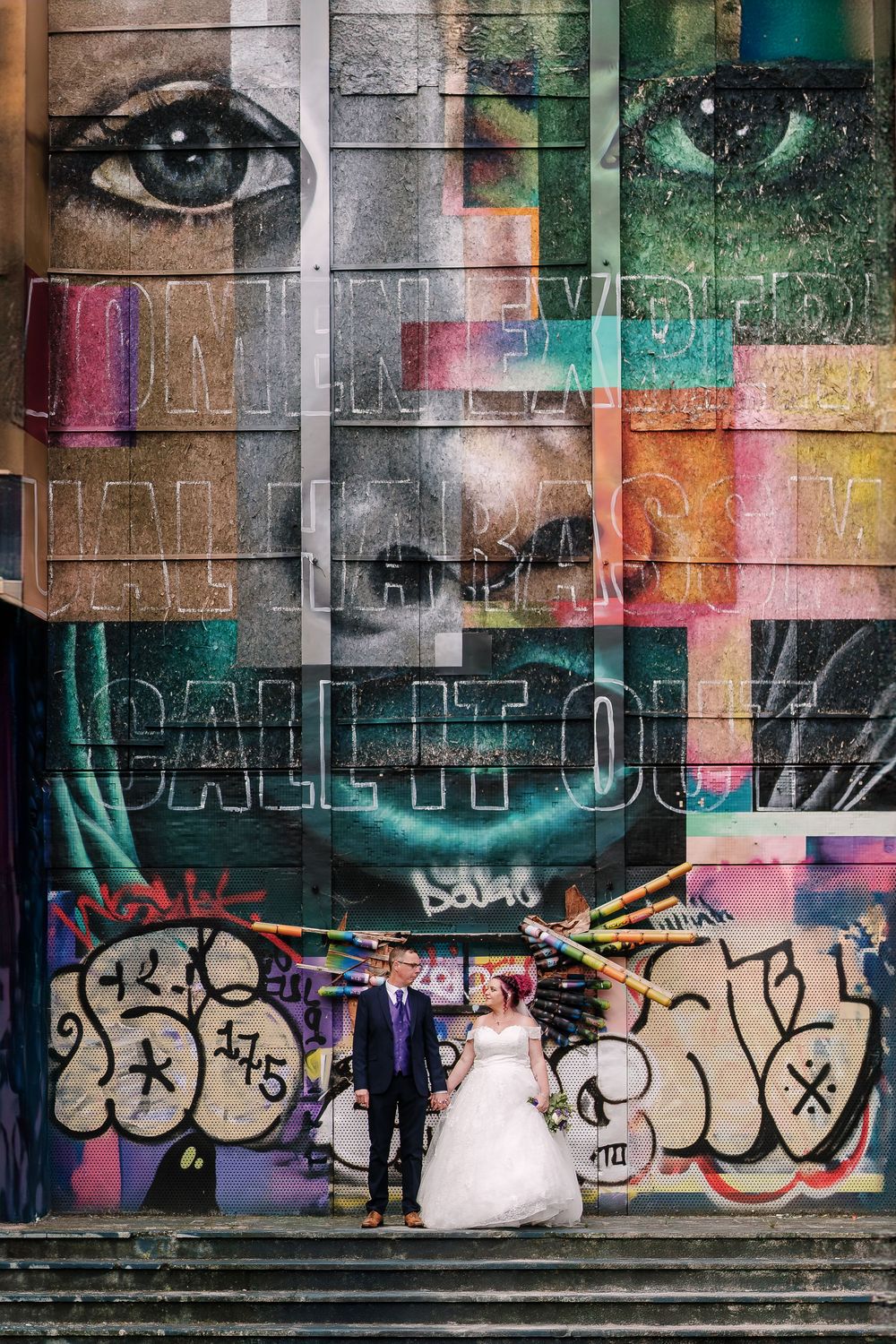 Bride and groom pose before a vibrant graffiti mural near Corn Street Registry Office Wedding, Bristol