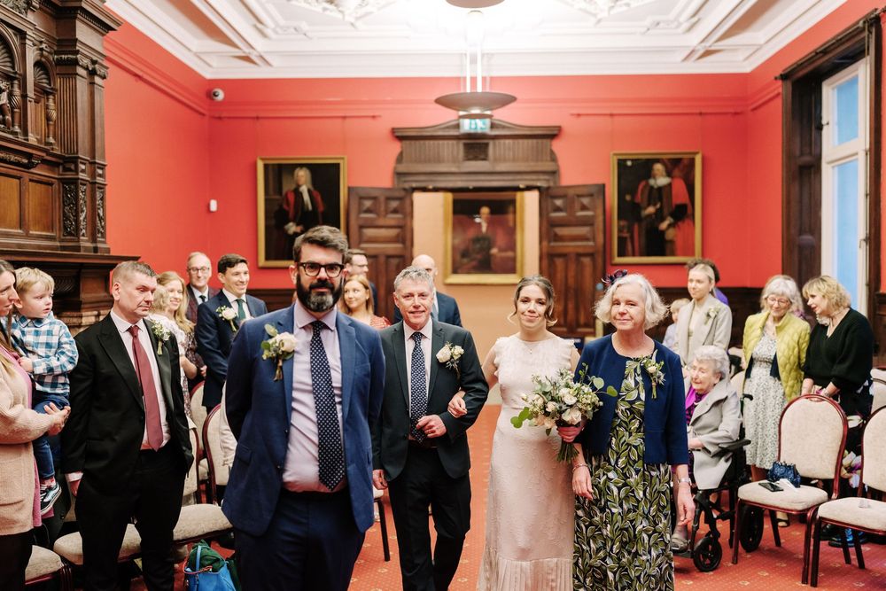 Wedding ceremony procession in Corn Street Registry Office Wedding, Bristol. Bride in ivory gown with bouquet.
