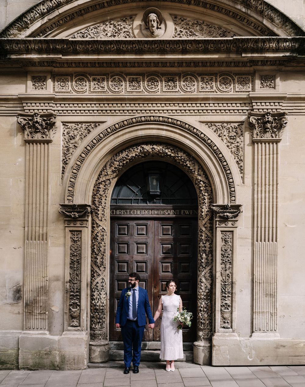 Bride and groom stand before ornate arched doorway for Corn Street Registry Office Wedding, Bristol