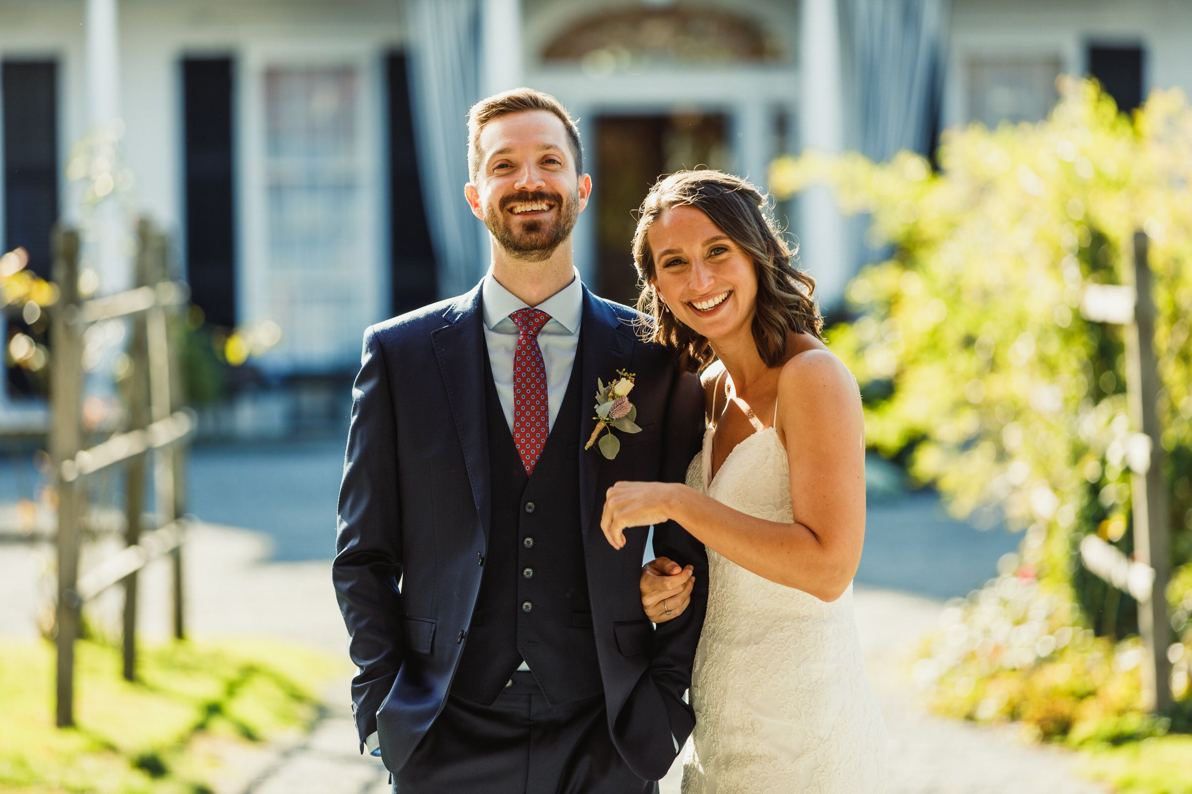 A couple in wedding attire standing in front of a stately mansion.