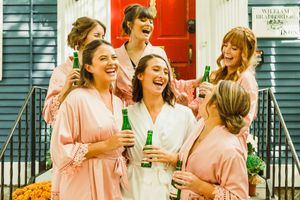 A group in pink robes sharing drinks and laughter on outdoor steps.