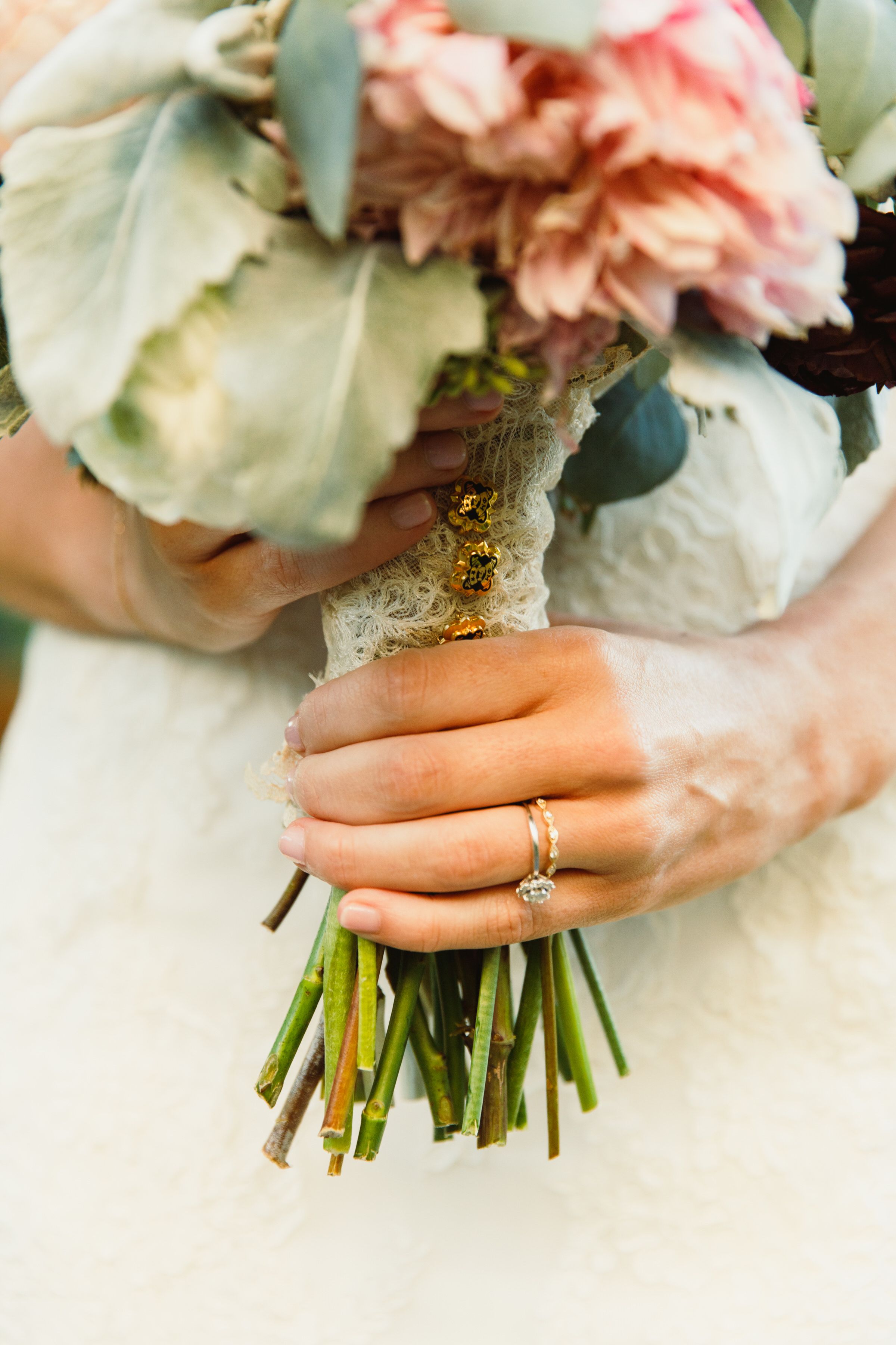 Close-up of hands holding a wedding bouquet with pink flowers, showing an engagement ring.