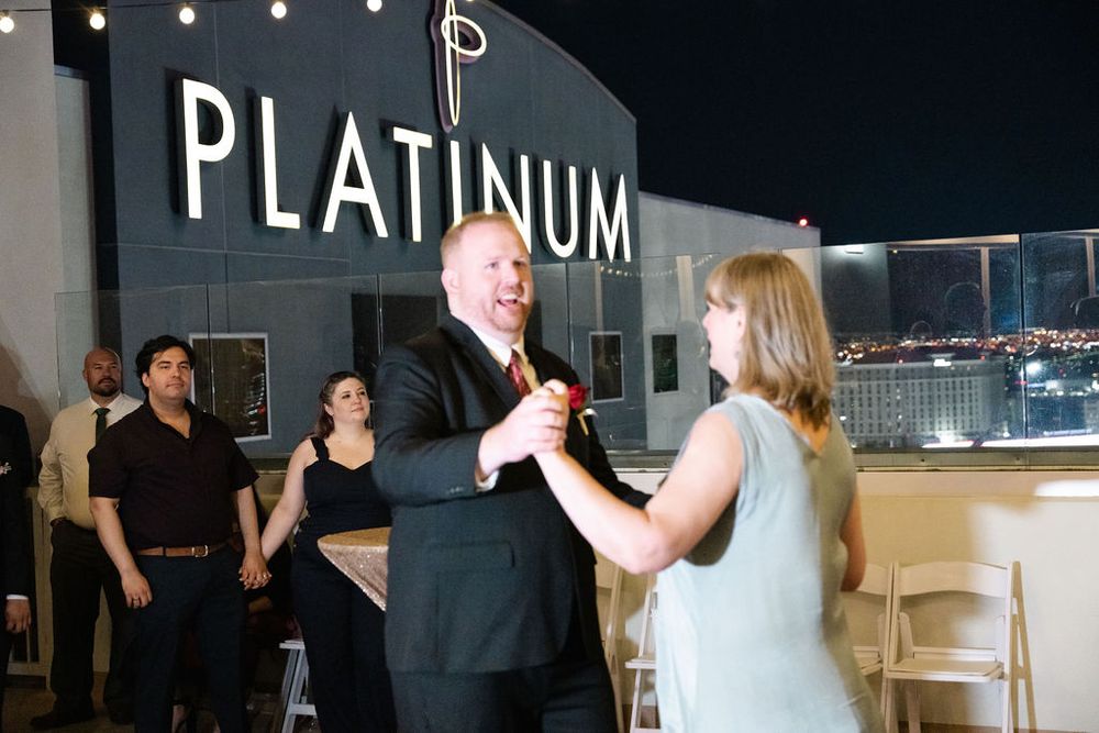 Couple dancing at Platinum venue rooftop event at night, with guests watching in background.